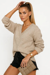 Woman wearing a black V-neck knit sweater with fitted black jeans